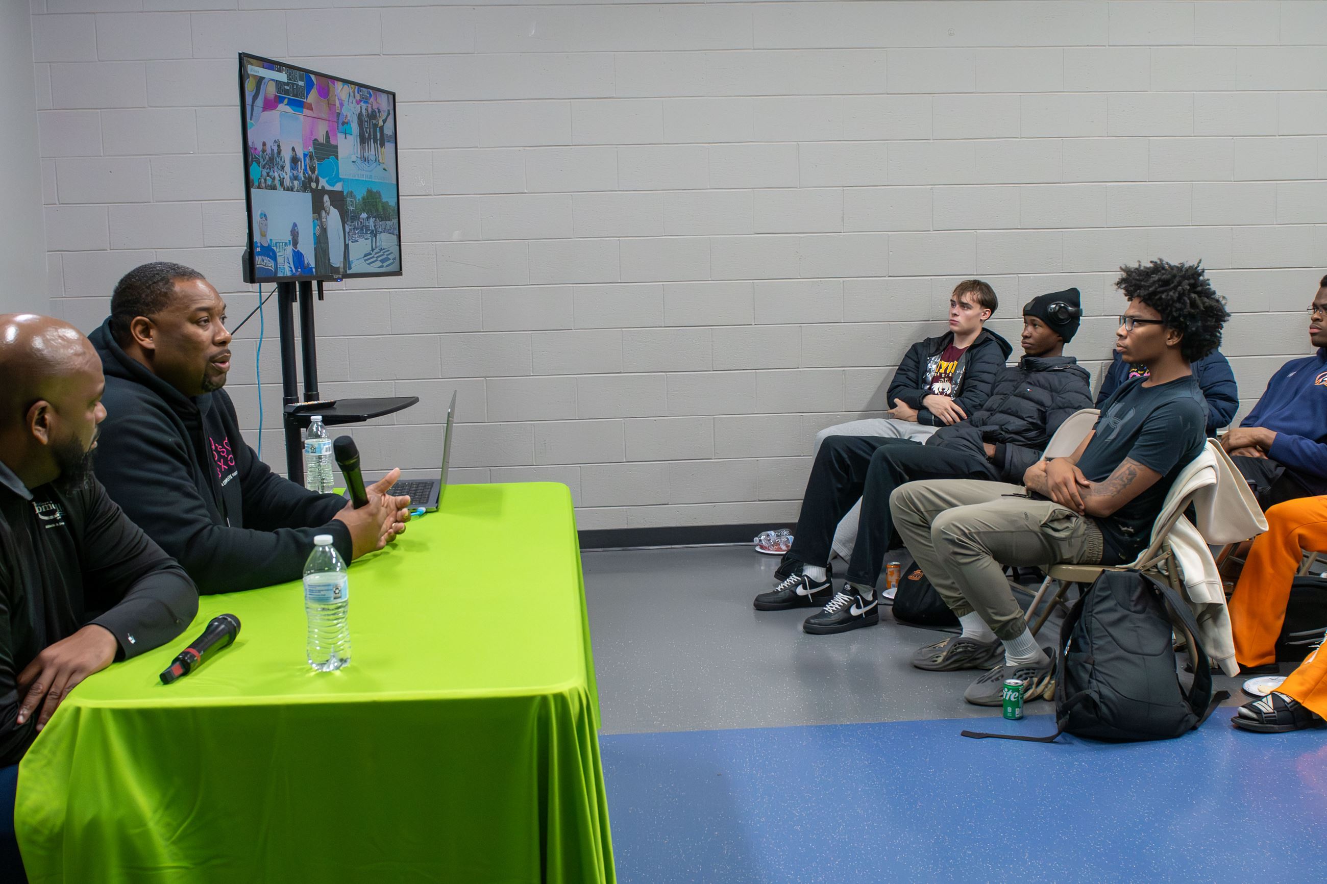 Two people sit at a table while the audience looks on.