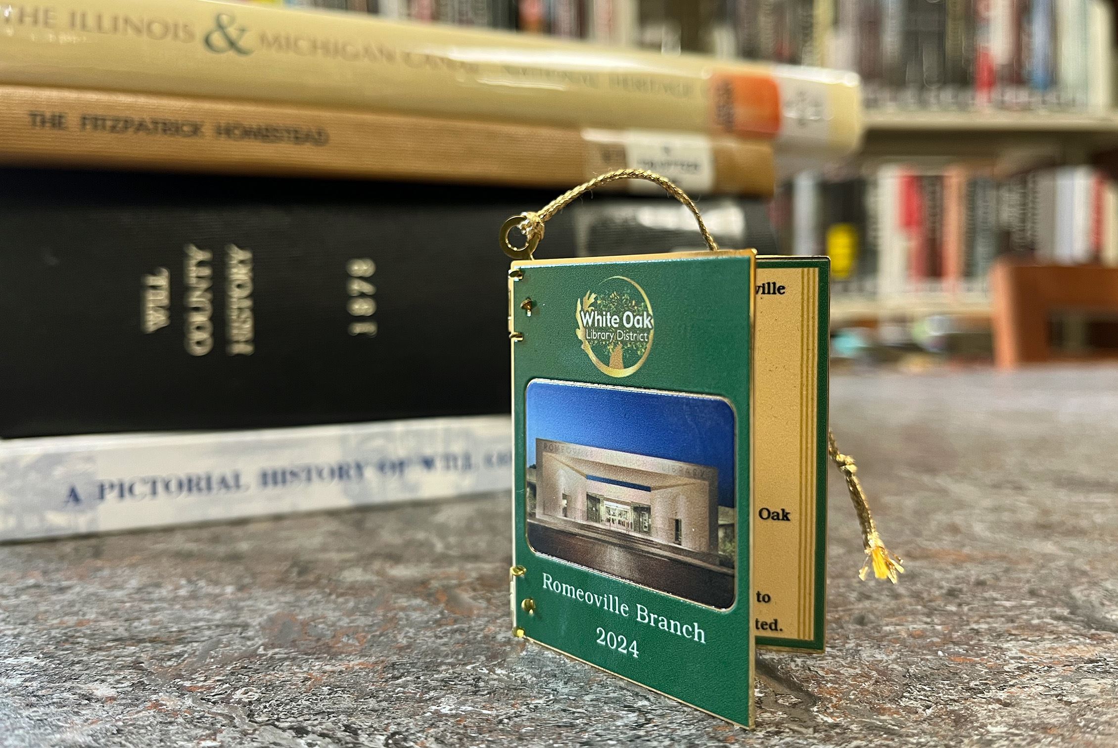 Library book ornament on a table with a stack of other books